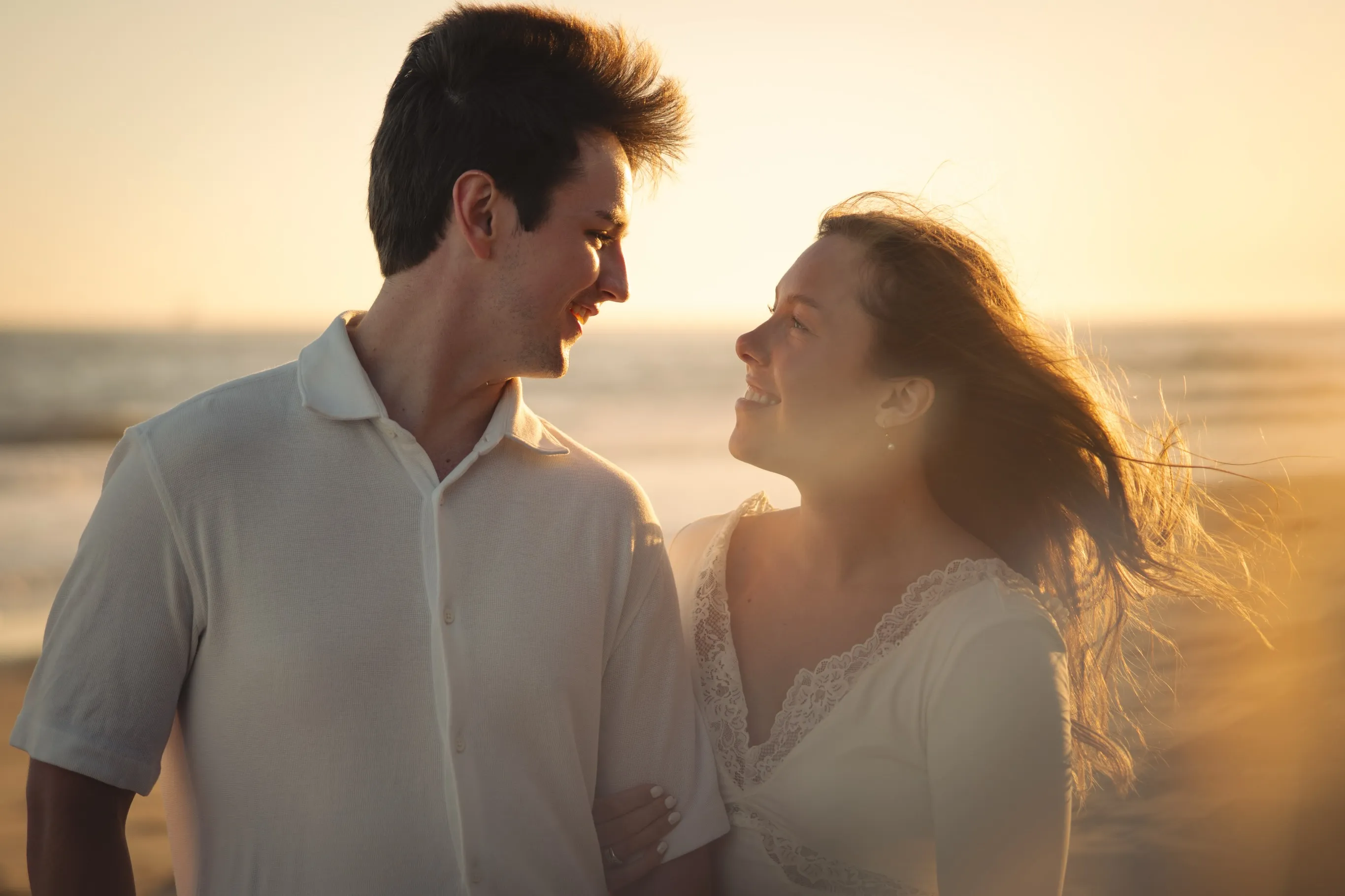 Engaged couple laughing together at golden hour