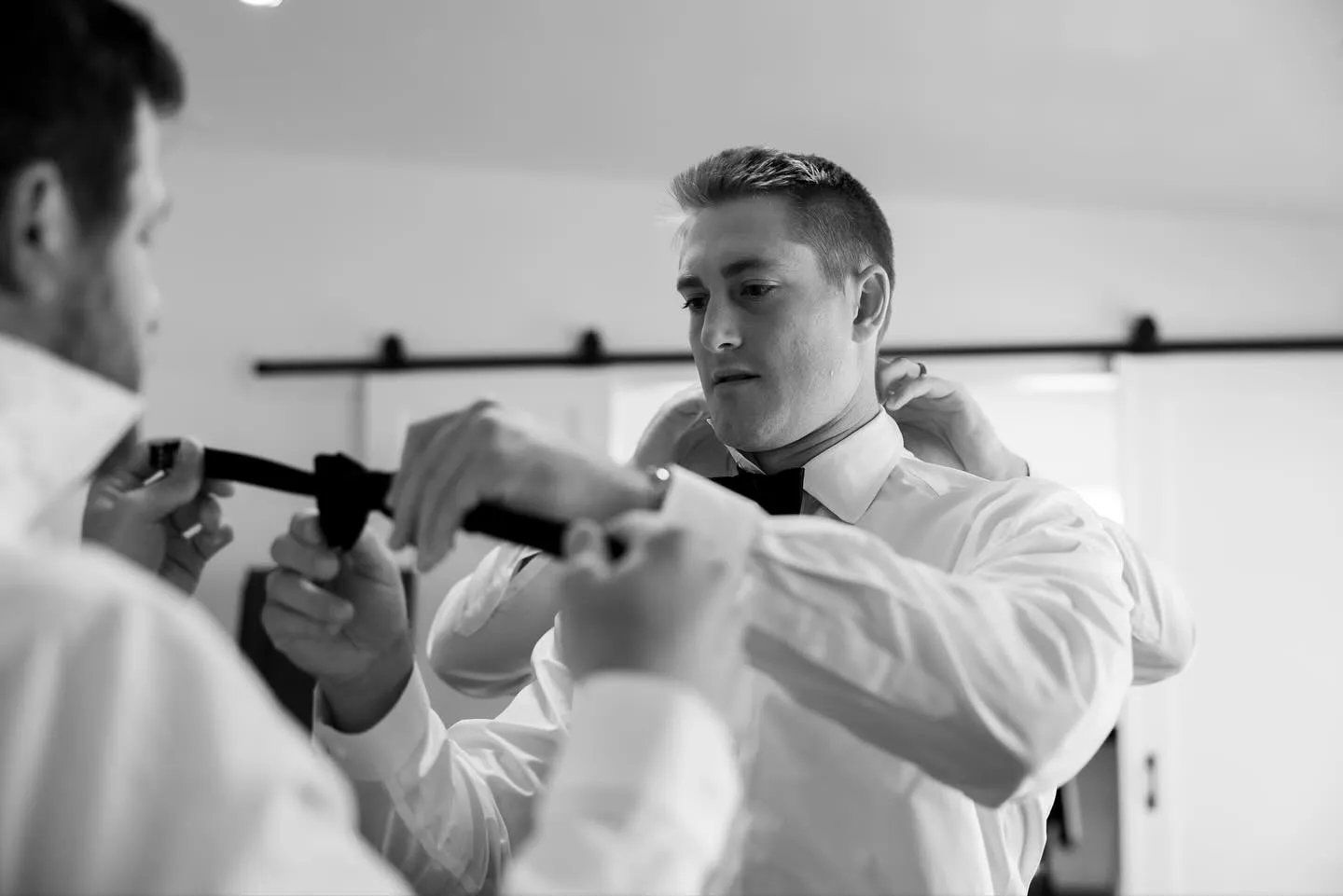 Black and white photo of a bow tie being fastened