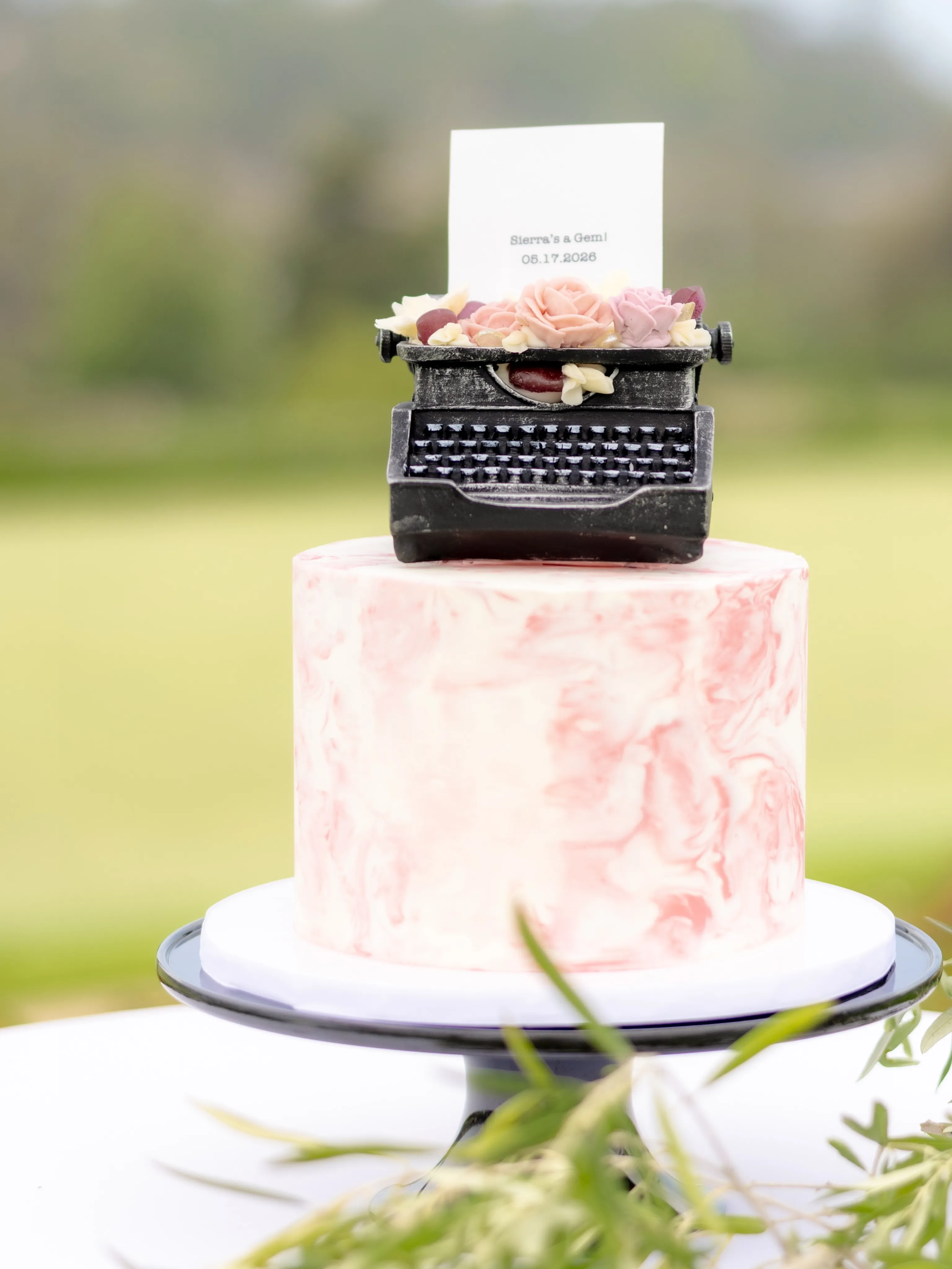 Pink celebration cake topped with a vintage typewriter