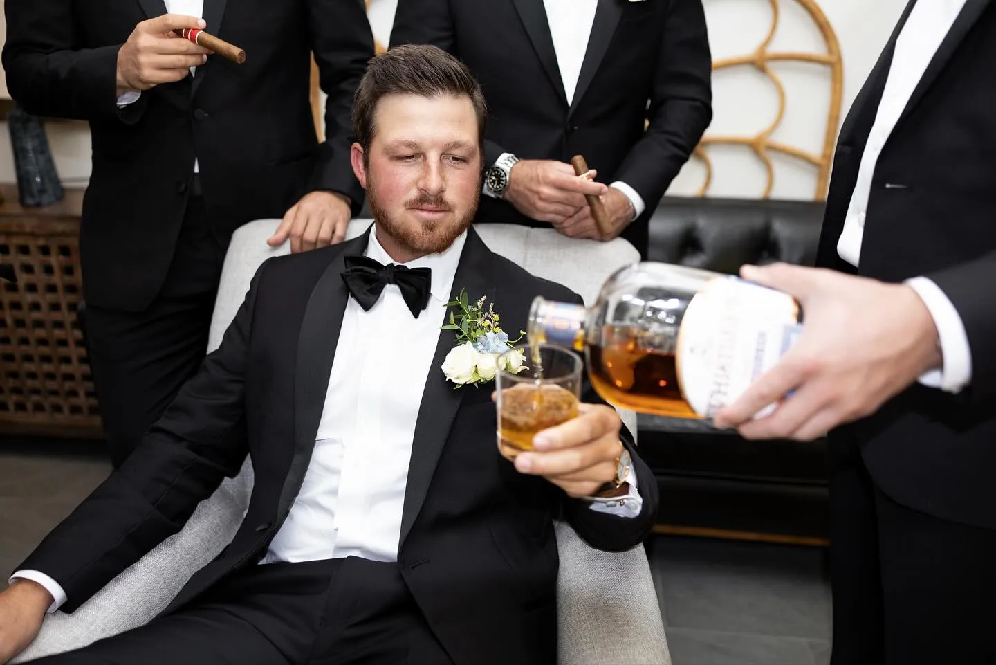 Groom being poured a whiskey while getting ready