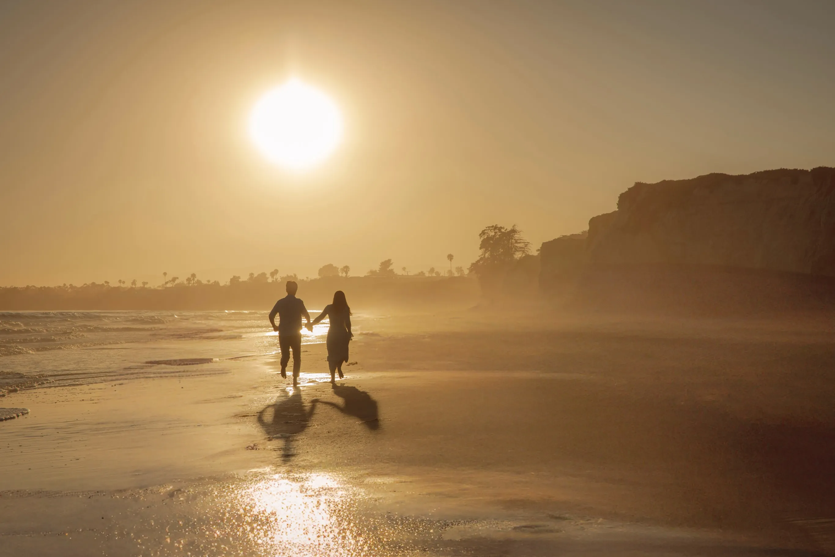 Couple walking along a Santa Barbara beach at sunset